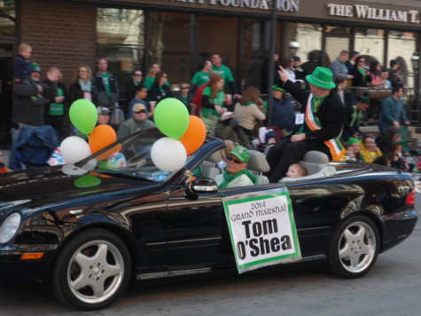 The 2014 Grand Marshal Tom O'Shea waves and smiles at the crowd, while the crowd goes wild and says hello to O'Shea. 