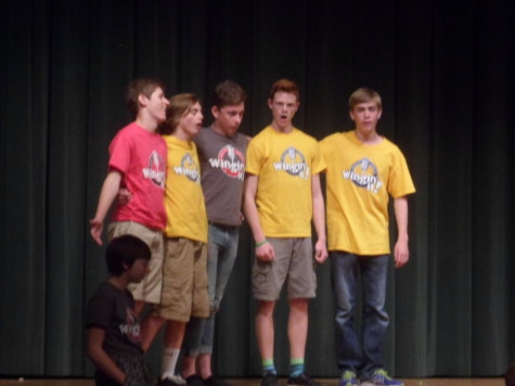 Seniors Ellis Johnson, Luke Bateman, junior Devin Stossmeister, sophomore Jules Harper-McCombs, and freshman Derek Ray sing backup in deep voices, trying to keep up with one of the members singing. 