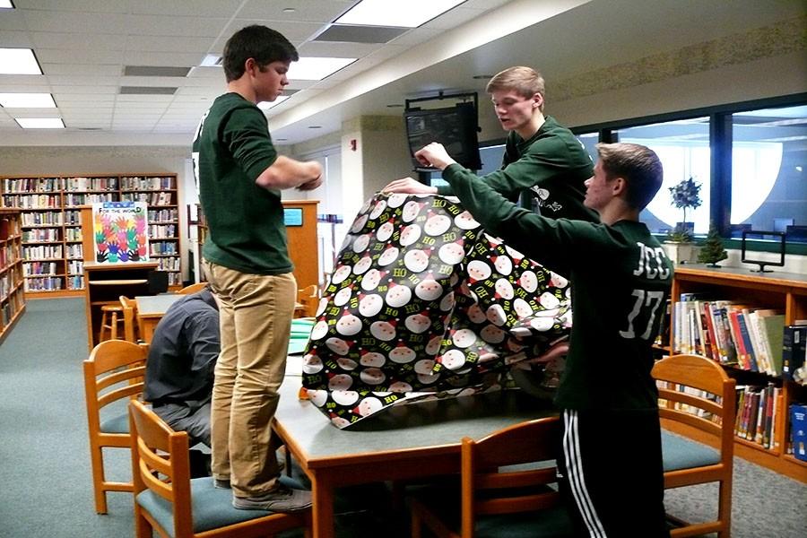 Juniors Josh Denlinger, Thomas Hallman, and Tyler Hallman work together to wrap a bike for Adopt a Family.