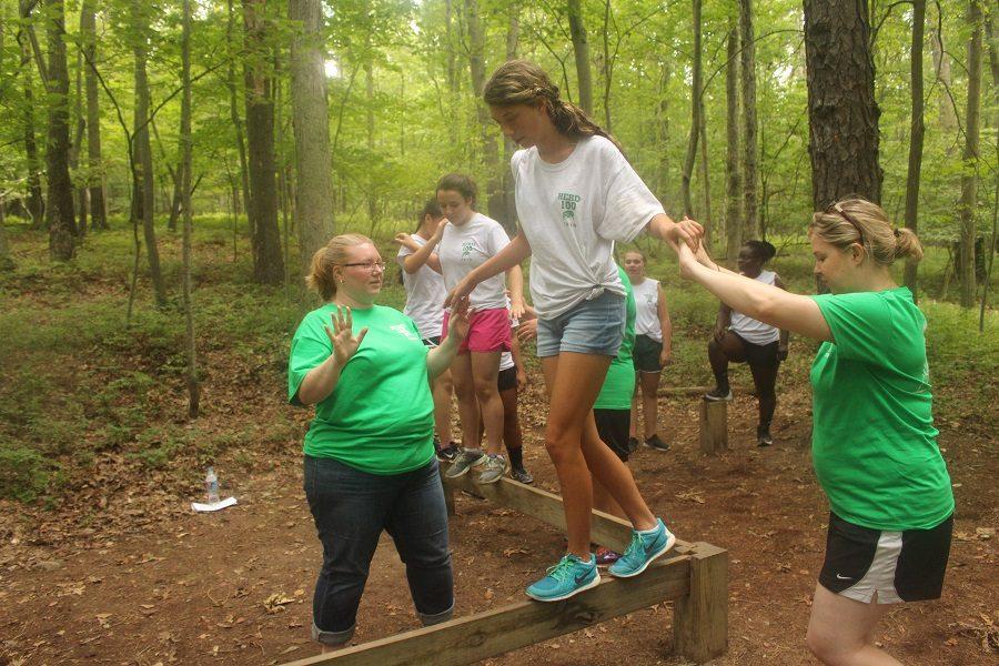 Carefully balancing, Abby Rossow, spotted by Kirsten McMahon and Stephanie Weimer, finishes the Zig Zag obstacle course without falling into the lava below.