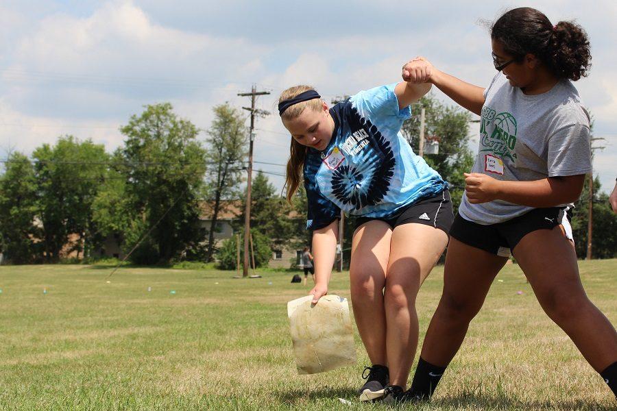 Rayvn Byers and Cierra Jones support each other as they make their way across the river with their few stepping stones.