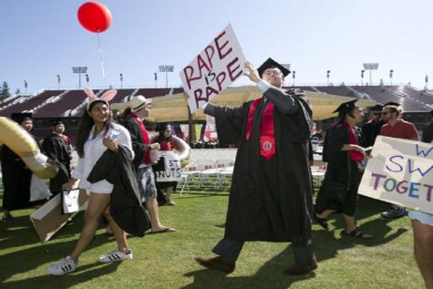 Paul Harrison, center, carries a counter-protest sign at the Stanford University graduation exercises, Sunday, June 12, 2016, at Stanford Stadium in Stanford, Calif. Women's advocacy organizations are urging a California agency to take action against the judge who sentenced a former Stanford University swimmer to six months in jail for sexually assaulting an unconscious woman. Harrison argued that the assault was not indicative of a "rape culture" at the university, and unfairly blamed the school for the attack by a man who just happened to be one of their students.(AP Photo/D. Ross Cameron)