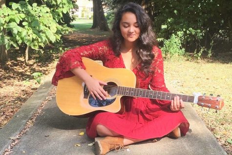 Freshman, Lauren Klepp strumming the guitar in a country tune. 