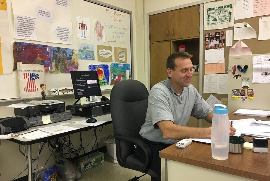 Mr. Chuck Roeder sits at his desk diligently grading papers. 