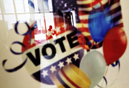 In this Nov. 1, 2016, photo, a voter is reflected in the glass frame of a poster while leaving a polling site in Atlanta, during early voting ahead of the Nov. 8 election day. If all goes smoothly, the American people will choose a new president on Tuesday, the Electoral College will affirm the election and either Democrat Hillary Clinton or Republican Donald Trump will take the oath of office Jan. 20.  (AP Photo/David Goldman)