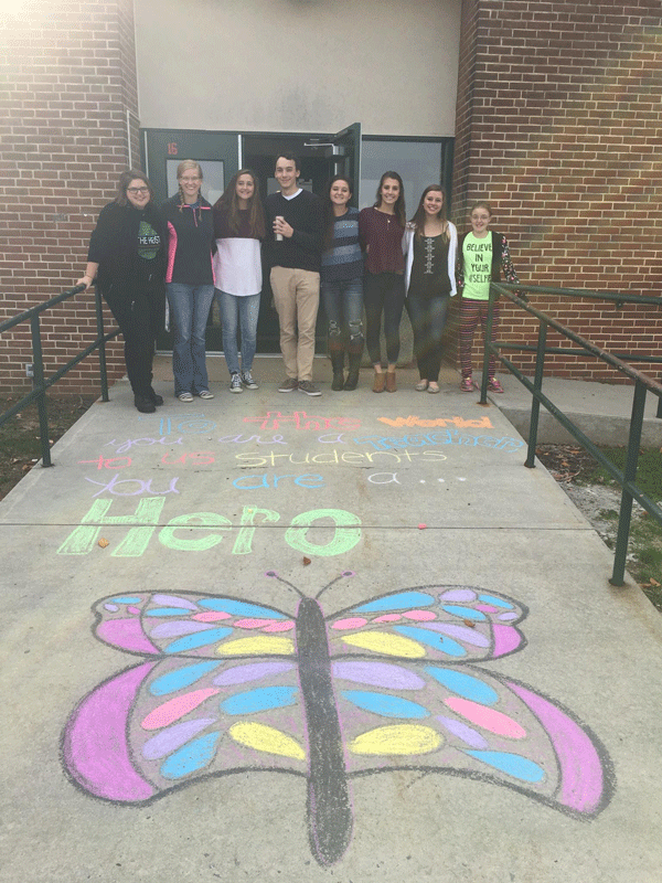 Members of the Aevidum club show off their handiwork.  They recently decorated sidewalks around McGowan with messages of thanks and encouragement.