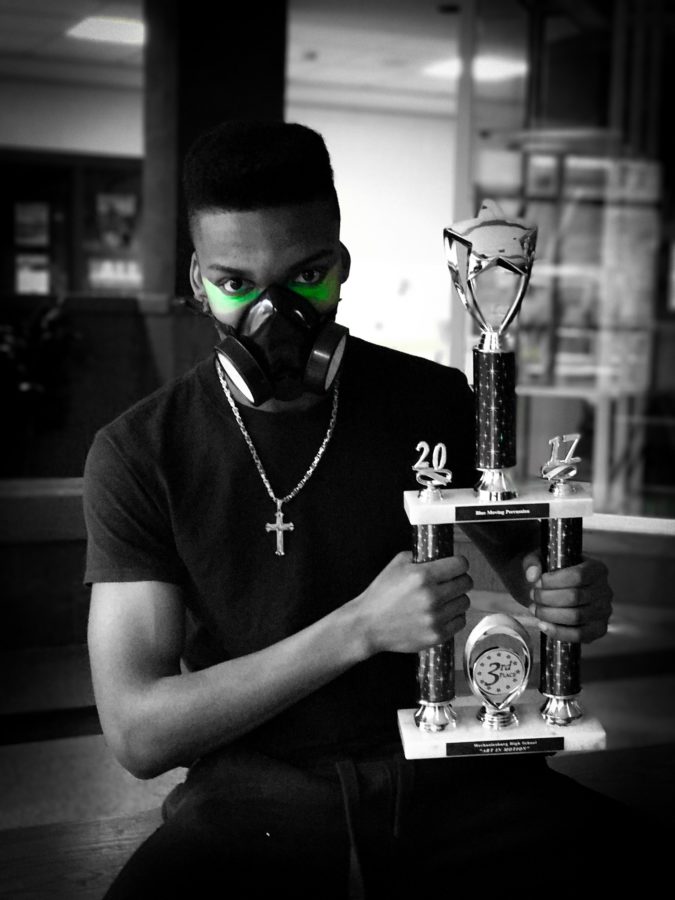 Senior Joe Brown poses with his gas mask while holding indoor percussions 3rd place trophy. 