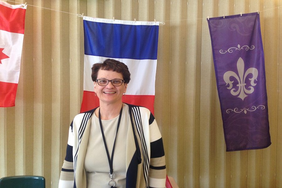 Madame Lathrop stands in front of her French Flag that is in her room. 