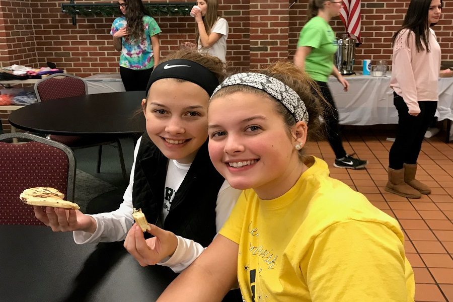 Grace Tollett and Paige Tollett enjoy their pancakes. Students in the club sold tickets and made the pancakes for the breakfast.