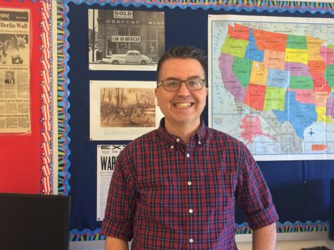 Michael Gavazzi stands in front of maps and documents in his classroom.