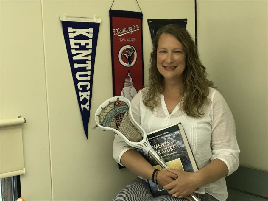 Michelle Disbrow poses with her college pennants, lacrosse stick, and English textbook in her classroom.