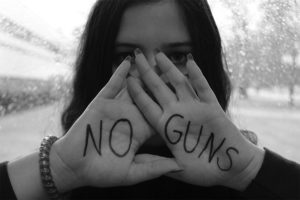 Sarah Rendon poses with a "NO GUNS" sign in support of the gun control movement.  This writer asks, why have we stopped talking about gun control?