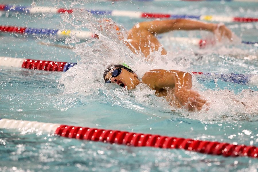 Isaiah Bell swims freestyle during a swim meet.  Bell is a senior captain on the varsity team this season.