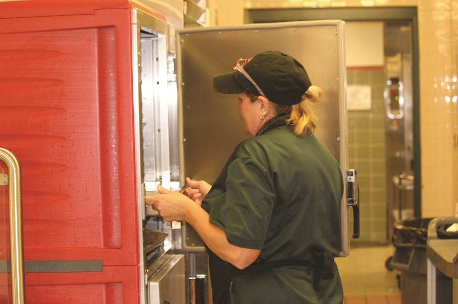 Deb Holly puts pizza in the oven, preparing for lunch. Pizza is a favorite in the Swartz cafeteria.