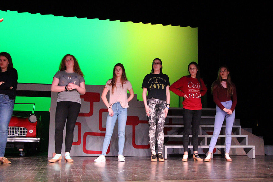 The ensemble of the show listens to feedback during the song, "Beauty School Dropout." During rehearsals, director Daniel Schade gives corrections and suggestions to the cast.
