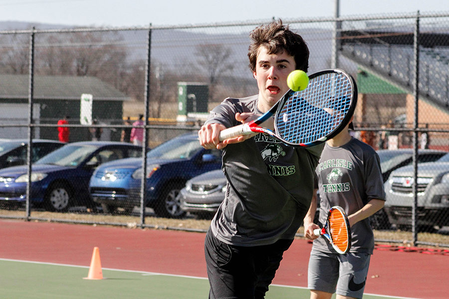 Varsity player James Kem stretches out to volley the tennis ball back over the net. He is a junior and is on the 2nd doubles team with Sean Bergsten. 