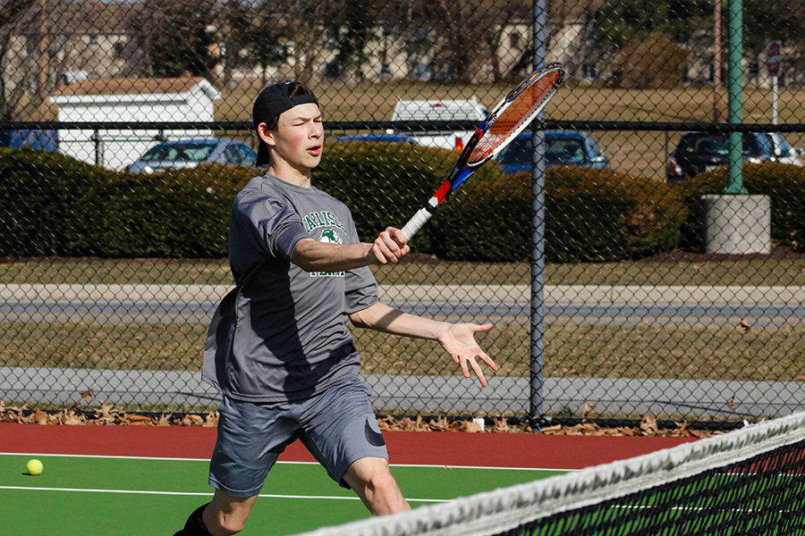 Varsity player Matthew Presite volleys a tennis ball over the tennis net. Presite is the number 2 singles player on the boys tennis team. 