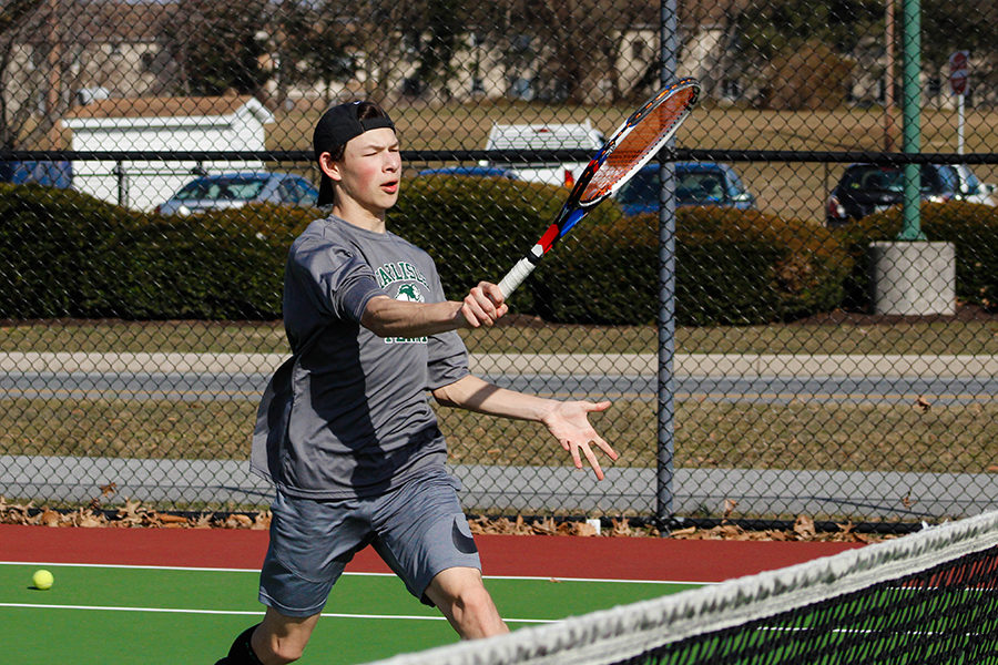 Varsity player Matthew Presite volleys a tennis ball over the tennis net. Presite is the number 2 singles player on the boy's tennis team. 