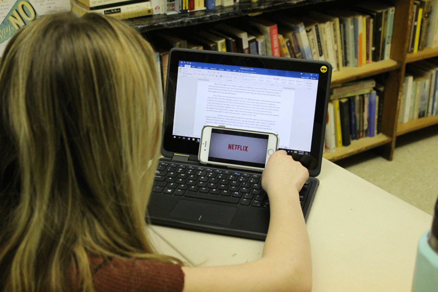 A student avoids her schoolwork by watching Netflix. Many students feel that they can afford to put off work due to the Quality Points system. 