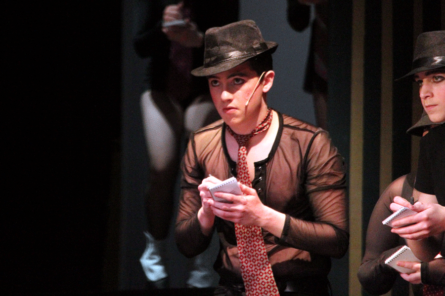  Senior Skylar Hammaker takes notes, as a reporter, while Roxie Hart explains why she had to kill Fred Casley.  This was Hammaker’s first musical, where he played both Fred Casley and a reporter in the ensemble.   