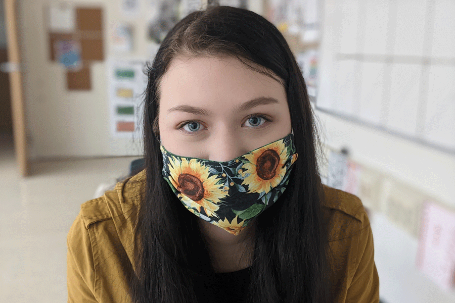 FLOWER POWER: Senior Audrey Crocker coordinates her sunflower mask with her jacket.  Many students find that picking out colorful, coordinating masks helps make the process of wearing them more bearable. For more mask photos, check out our Gallery. 
