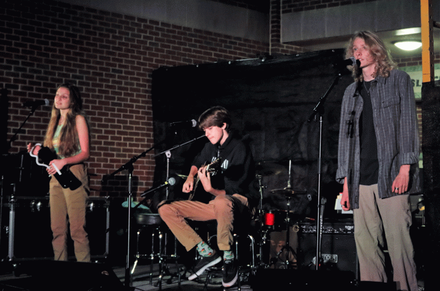 FLOORING AUDIENCES: Senior Renee Blacksmith and juniors Charlie Carlton and James Crawford take to the stage at the First Cup Coffeehouse performance night. Members of the band Under the Floorboards, they performed Somethin’ Stupid” by Frank and Nancy Sinatra. 