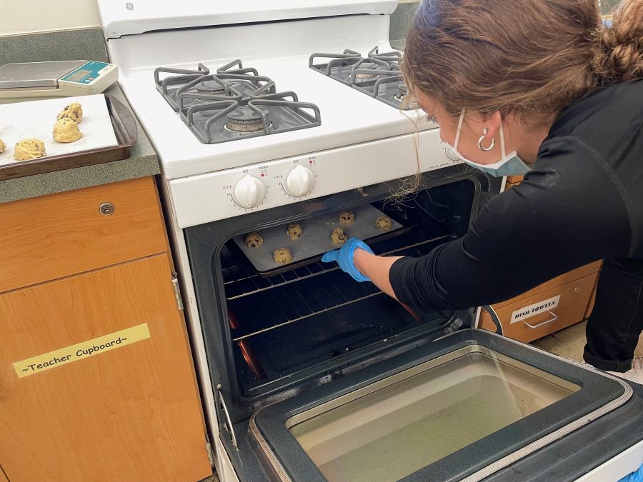 CLASS HEATS UP: Sophomore Maia Iannuzzi puts her groups classwork in the oven to hopefully create the perfect chocolate chip cookie.