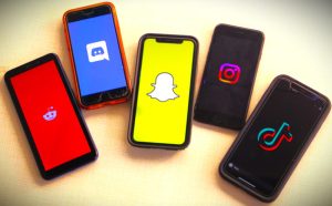 five phones displaying the start screens of social media apps