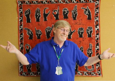 Mr. McGuire stands in front of his American Sign Language (ASL) alphabet banner hung in his classroom.