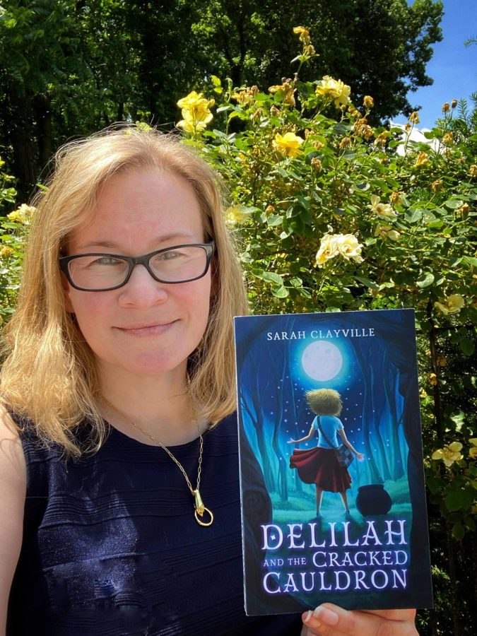 Ms. Clayville poses with her book, Delilah and the Cracked Cauldron. 