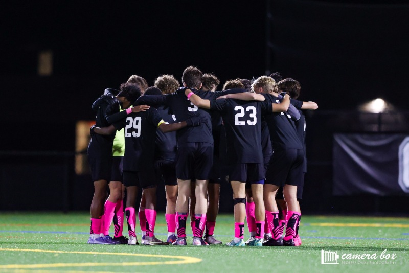 HUDDLE UP: The boys huddle together and discuss their plans for the game. Theyre seen repping bright pink socks for breast cancer awareness.