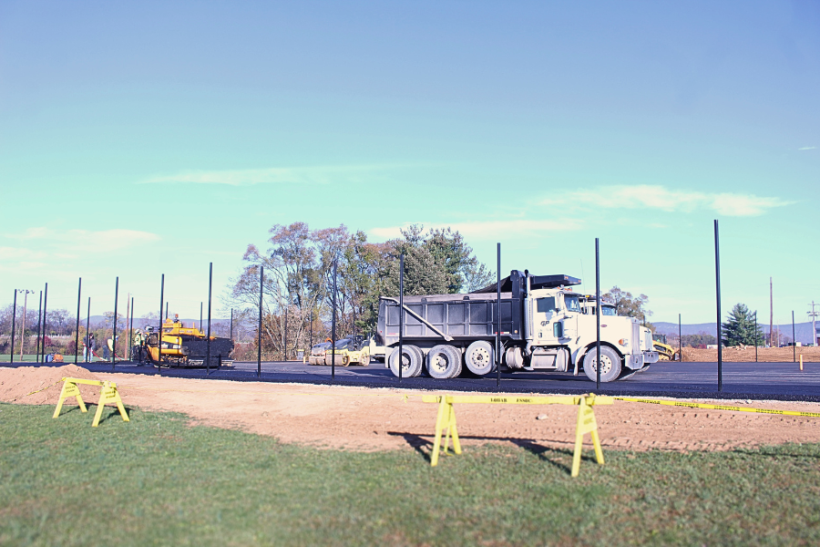 Construction workers are laying down asphalt for the new tennis courts.