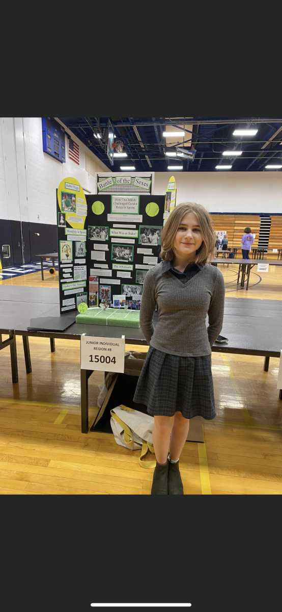 8th grade student, Bailey Clayville, stands next to her History Day project. Clayvilles project focuses on the impact of Billie Jean King as an icon of change in the realm of womens sports. 
