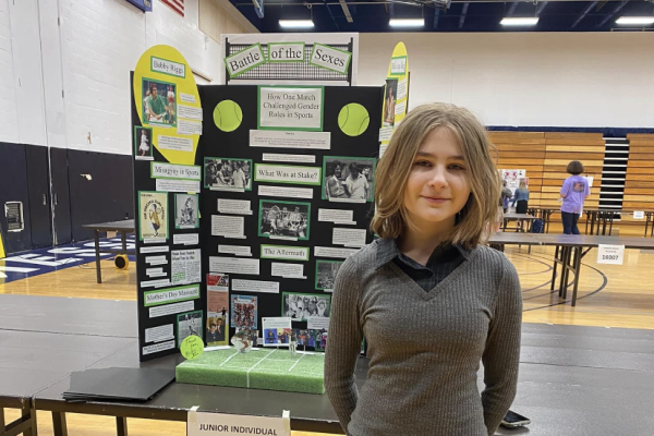 8th grade student, Bailey Clayville, stands next to her History Day project. Clayvilles project focuses on the impact of Billie Jean King as an icon of change in the realm of womens sports. 