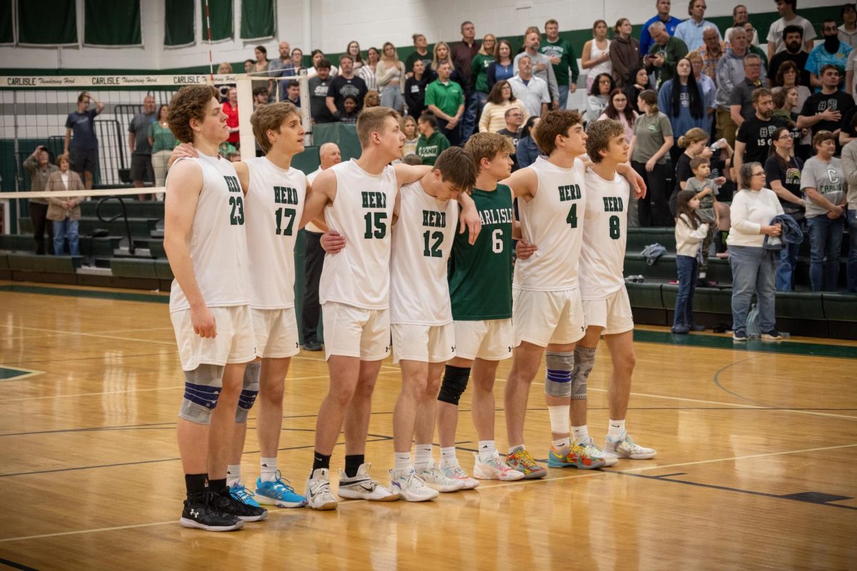 UNITED: The volleyball team stands for the national anthem, arms around one another.