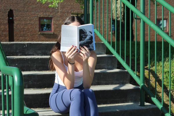 Student reads book on stairs completely engaged in the novel. "On Earth We're Briefly Gorgeous" is the perfect spring to summer read. 